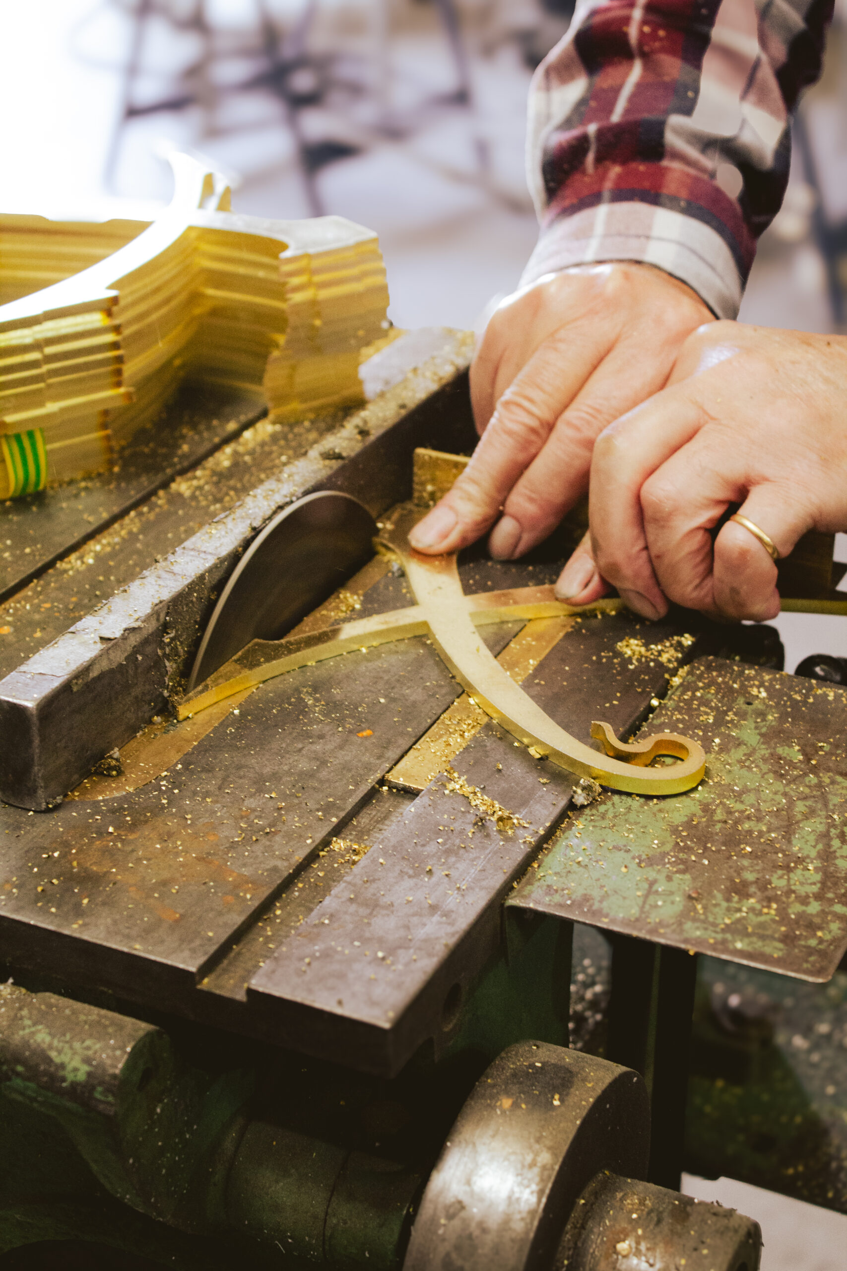 Découpe manuelle d&apos;une pièce en laiton à la scie circulaire dans un atelier d&apos;artisanat métallique, illustrant le savoir-faire traditionnel et la précision du travail artisanal