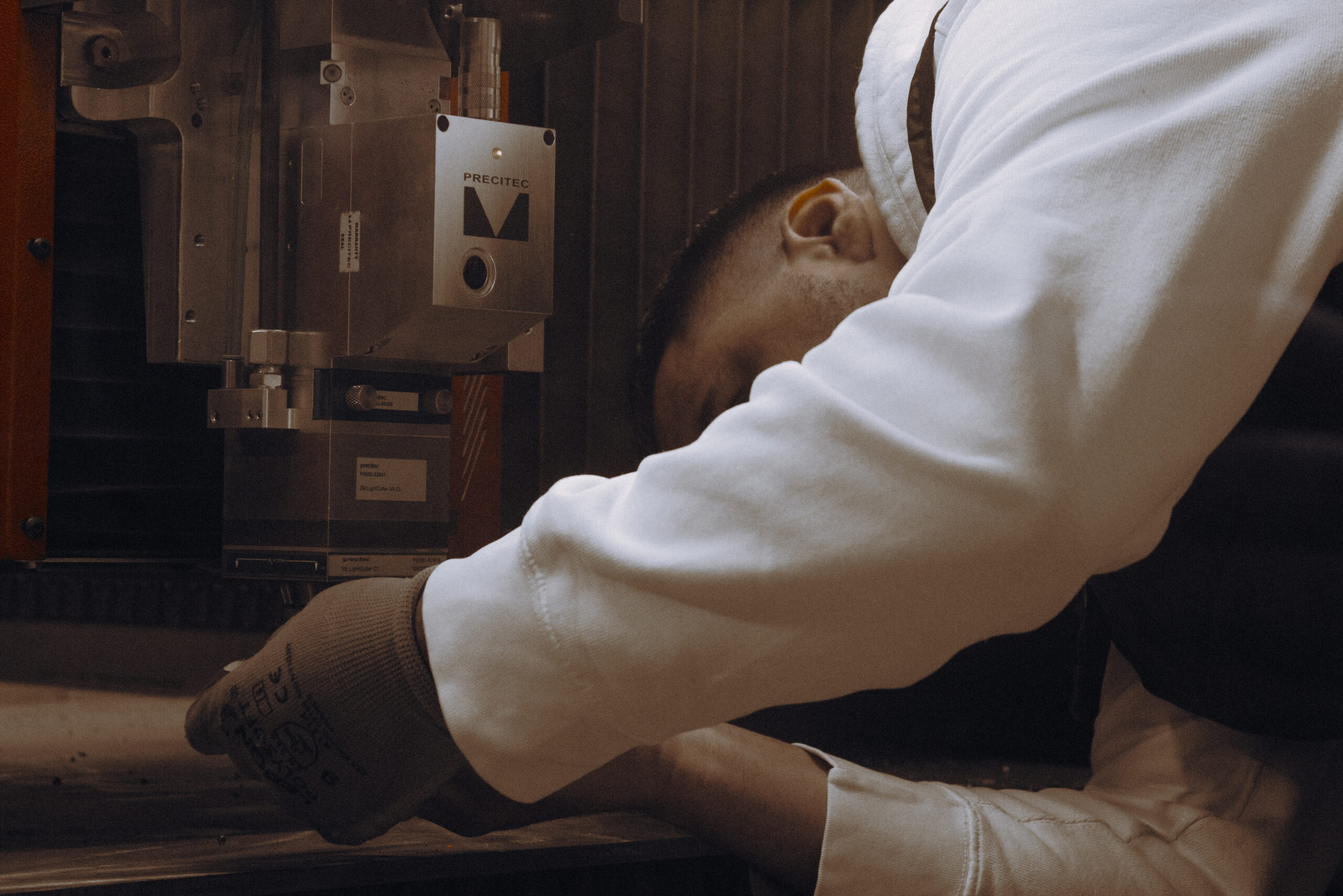 Technicien réglant une machine de découpe laser de précision dans un atelier de fabrication de luminaires haut de gamme