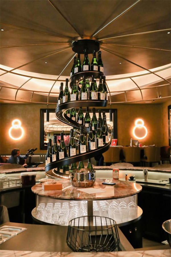 Création lumineuse sculpturale intégrant une spirale de bouteilles, luminaire design sur mesure pour bar haut de gamme